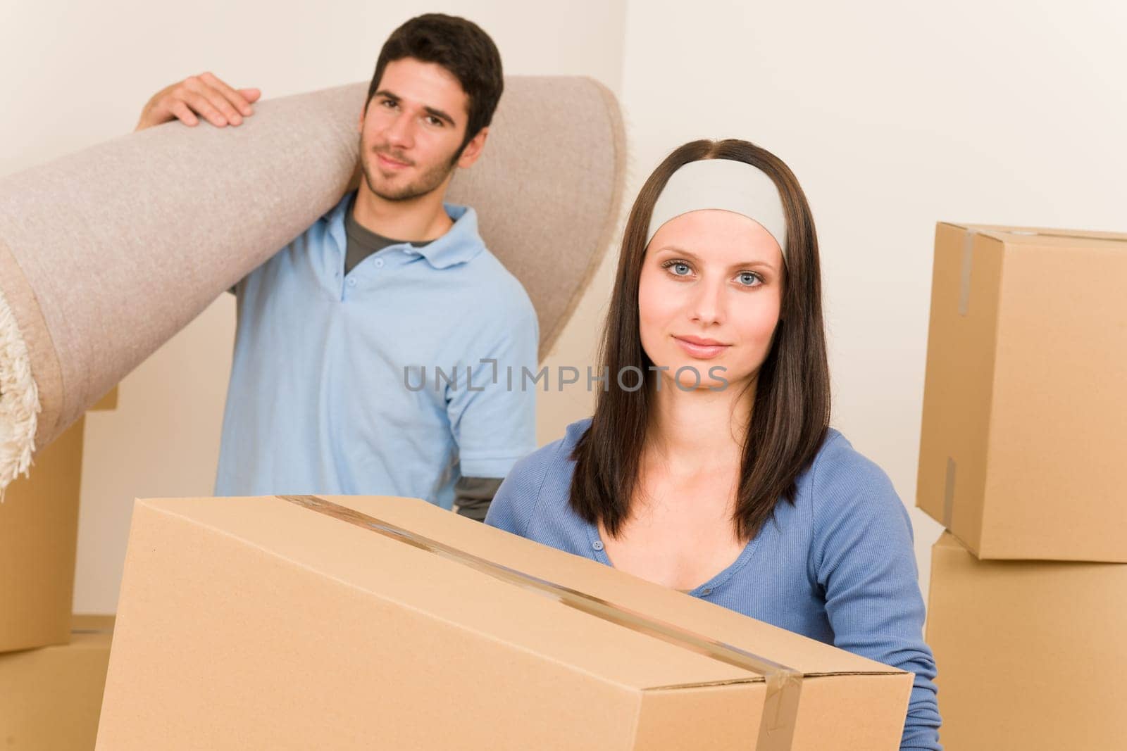 Happy couple with boxes and carpet moving into new home
