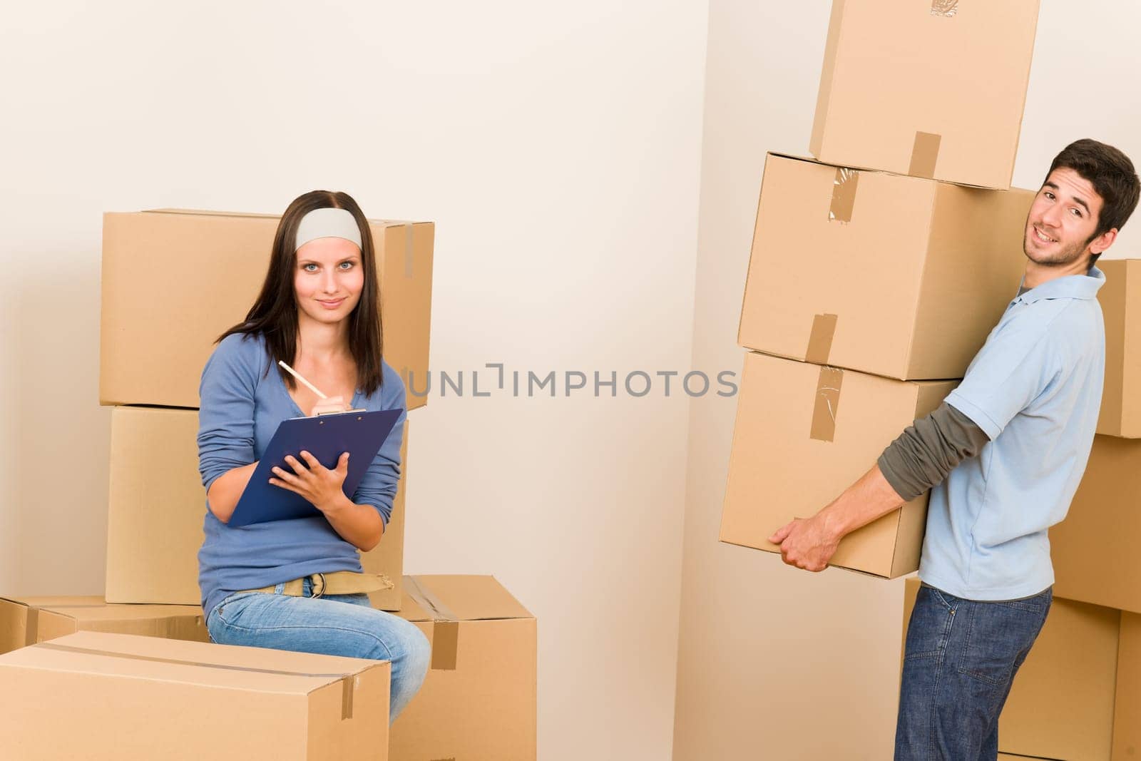 Happy young couple moving into new home carrying cardboard boxes