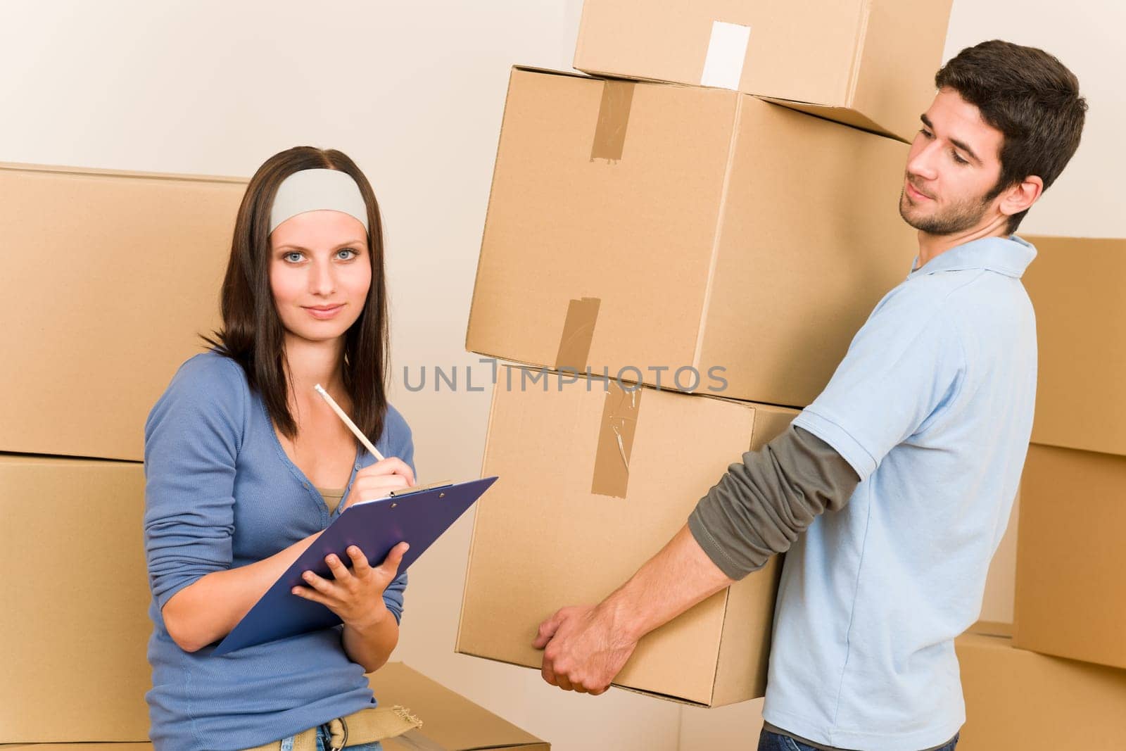 Happy young couple moving into new home carrying cardboard boxes