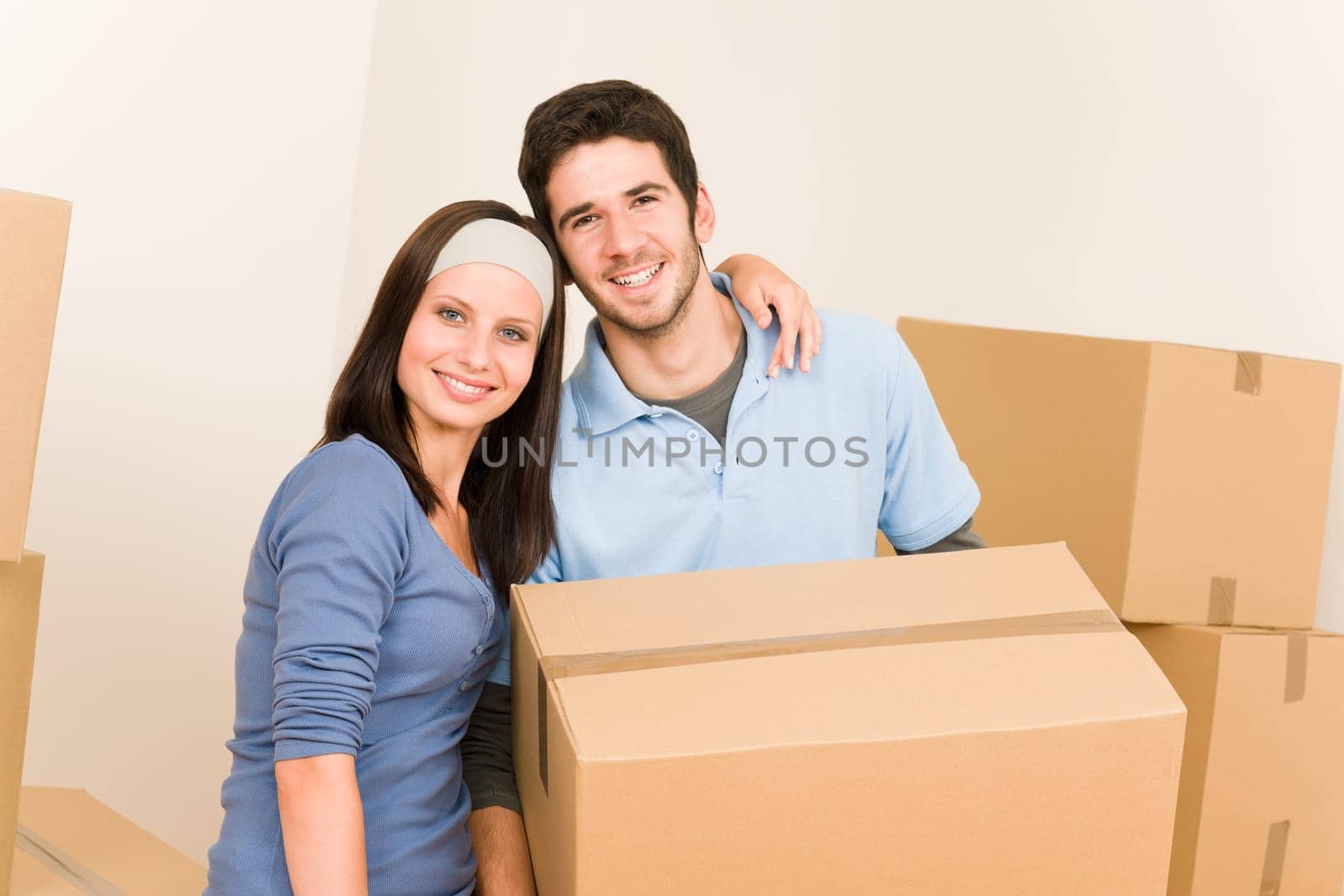 Happy young couple moving into new home carrying cardboard boxes