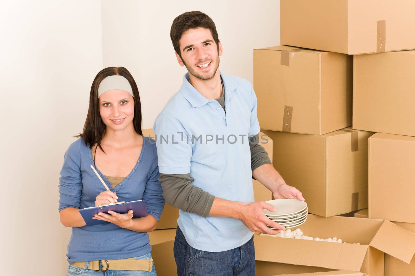 Moving new home young happy couple unpacking cardboard boxes together