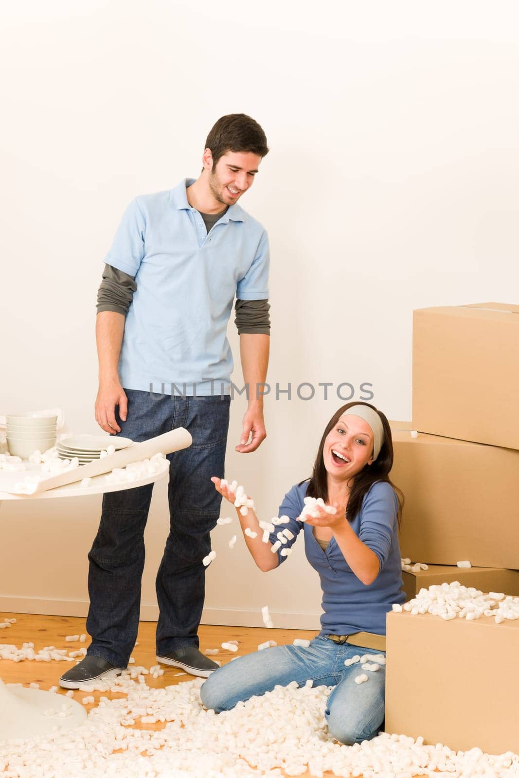 Moving new home young cheerful couple unpacking cardboard boxes together