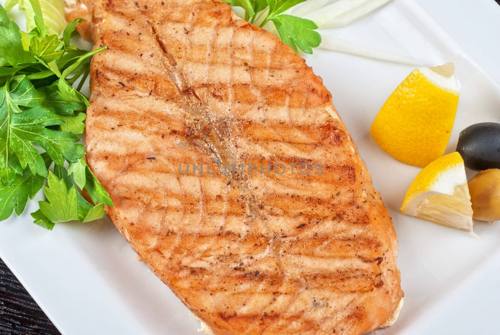 Grilled salmon steak with greens,onion, lemon, lime and olive