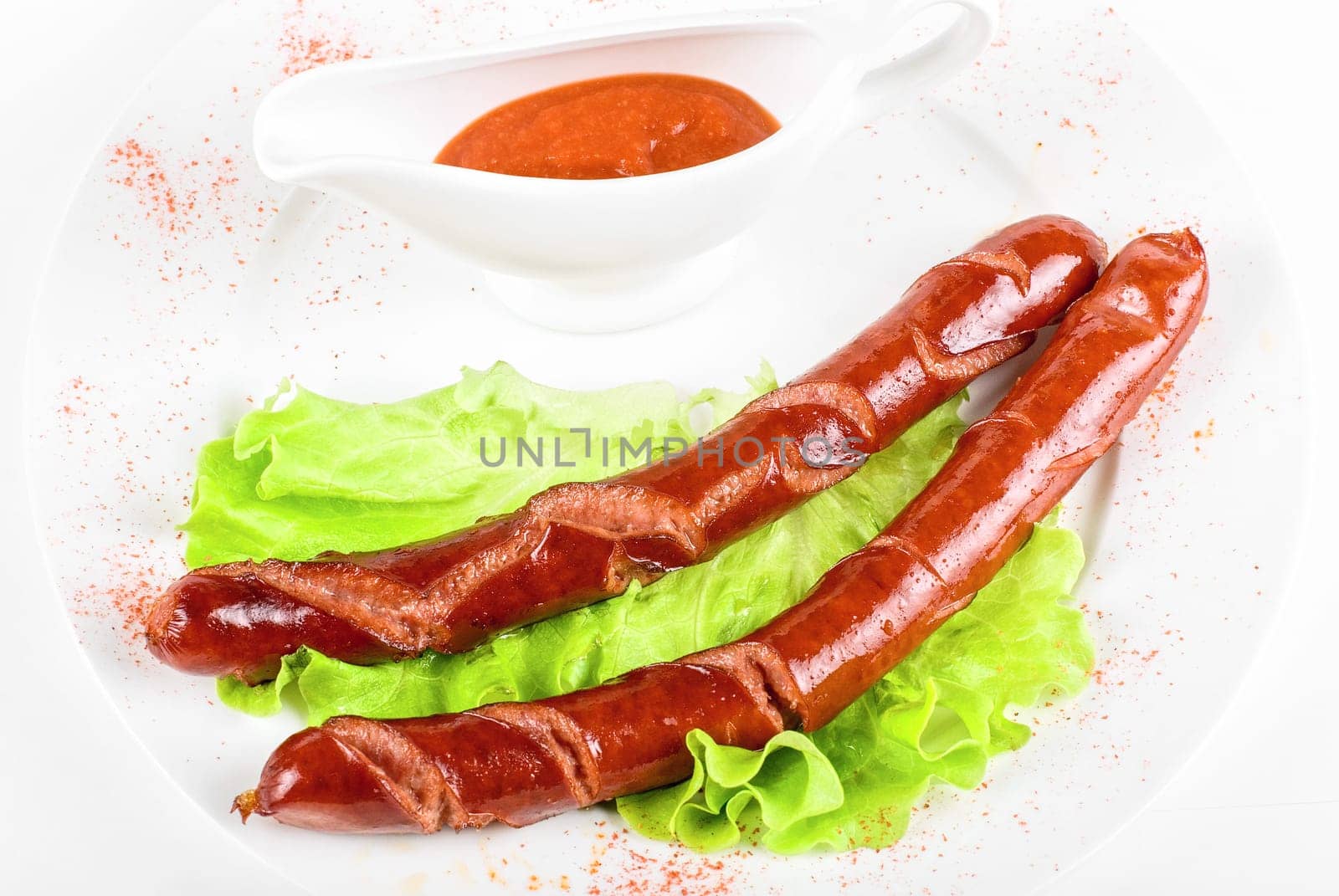 grilled sausages closeup with lettuce and sauce isolated on white