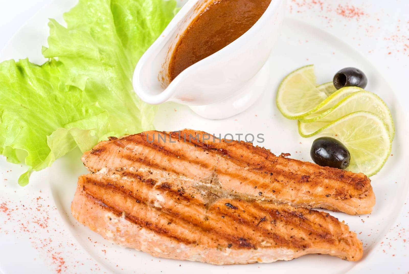 Grilled salmon steak with sauce,greens, lemon and olive