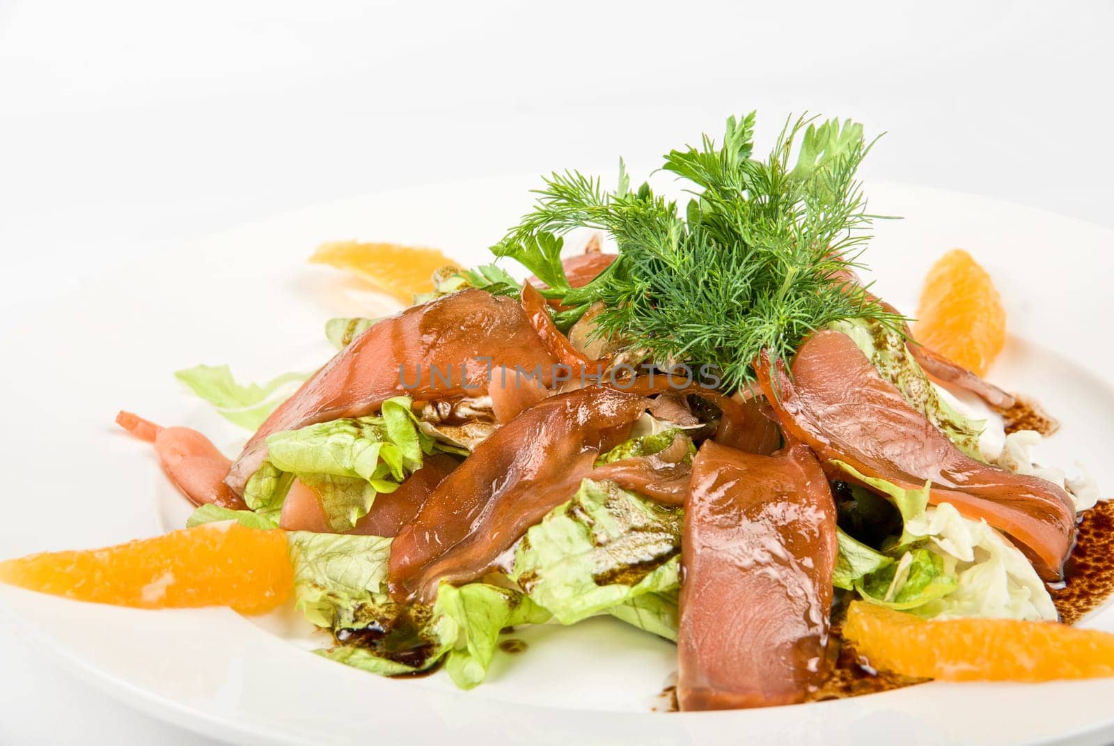 Tasty salad dish close up with fish and oranges on a white background
