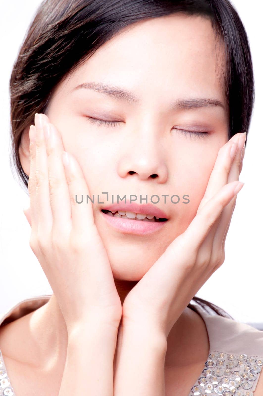 Young asian female with her hands on face in beauty shot