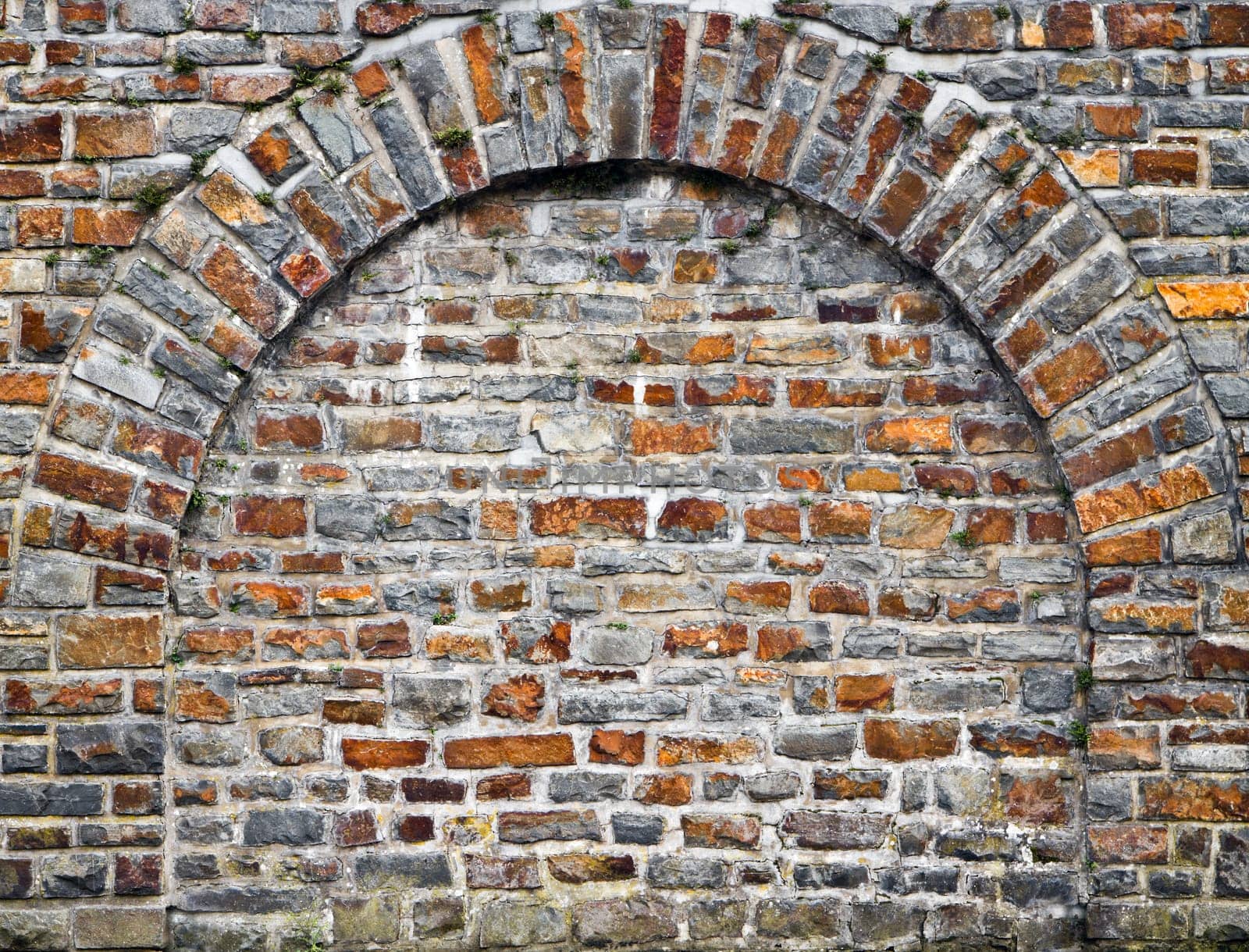 Old bricks stonewall from cut out rocks with arched brickwork