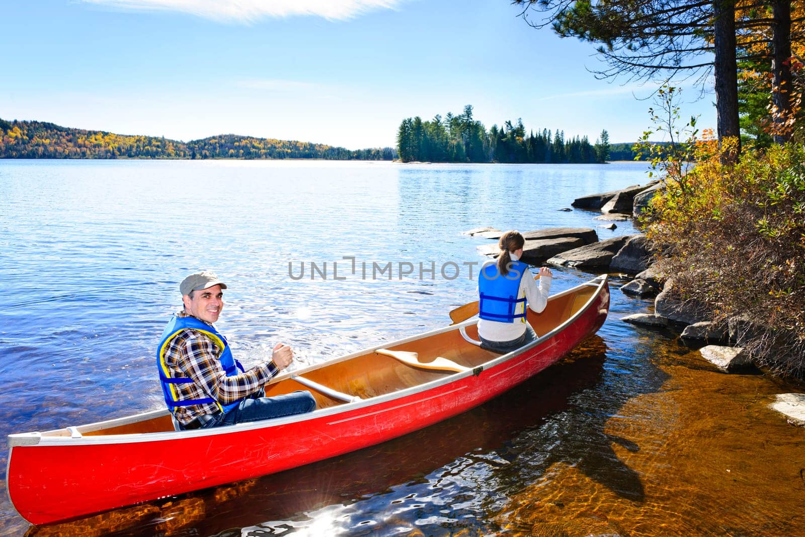 Family in red canoe near rocky shore of Lake of Two Rivers, Ontario, Canada