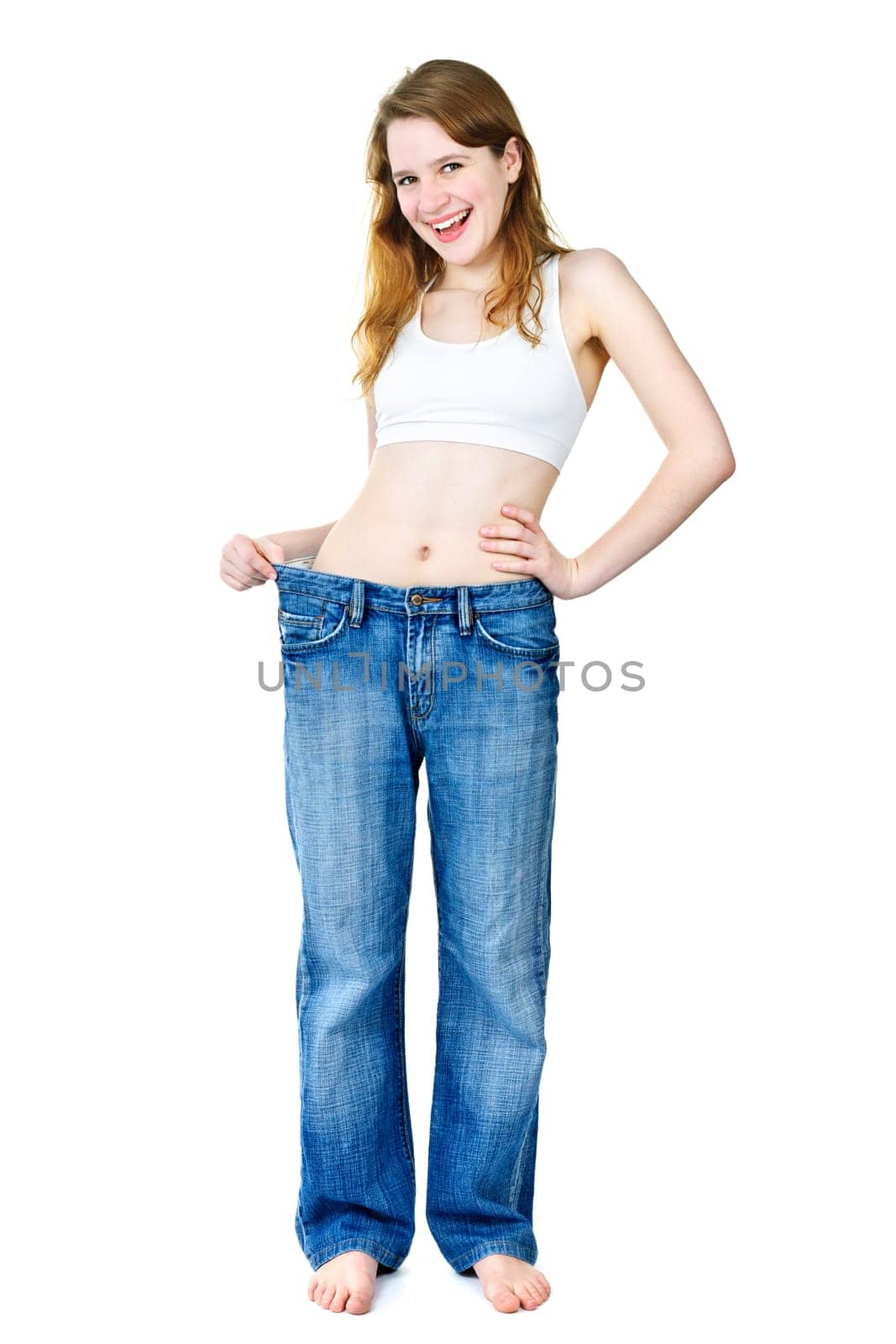Happy fit young woman in loose old jeans after losing weight isolated on white