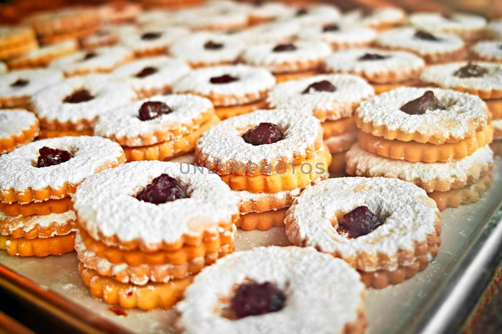Jam sandwich cookies stacked on a cookie sheet