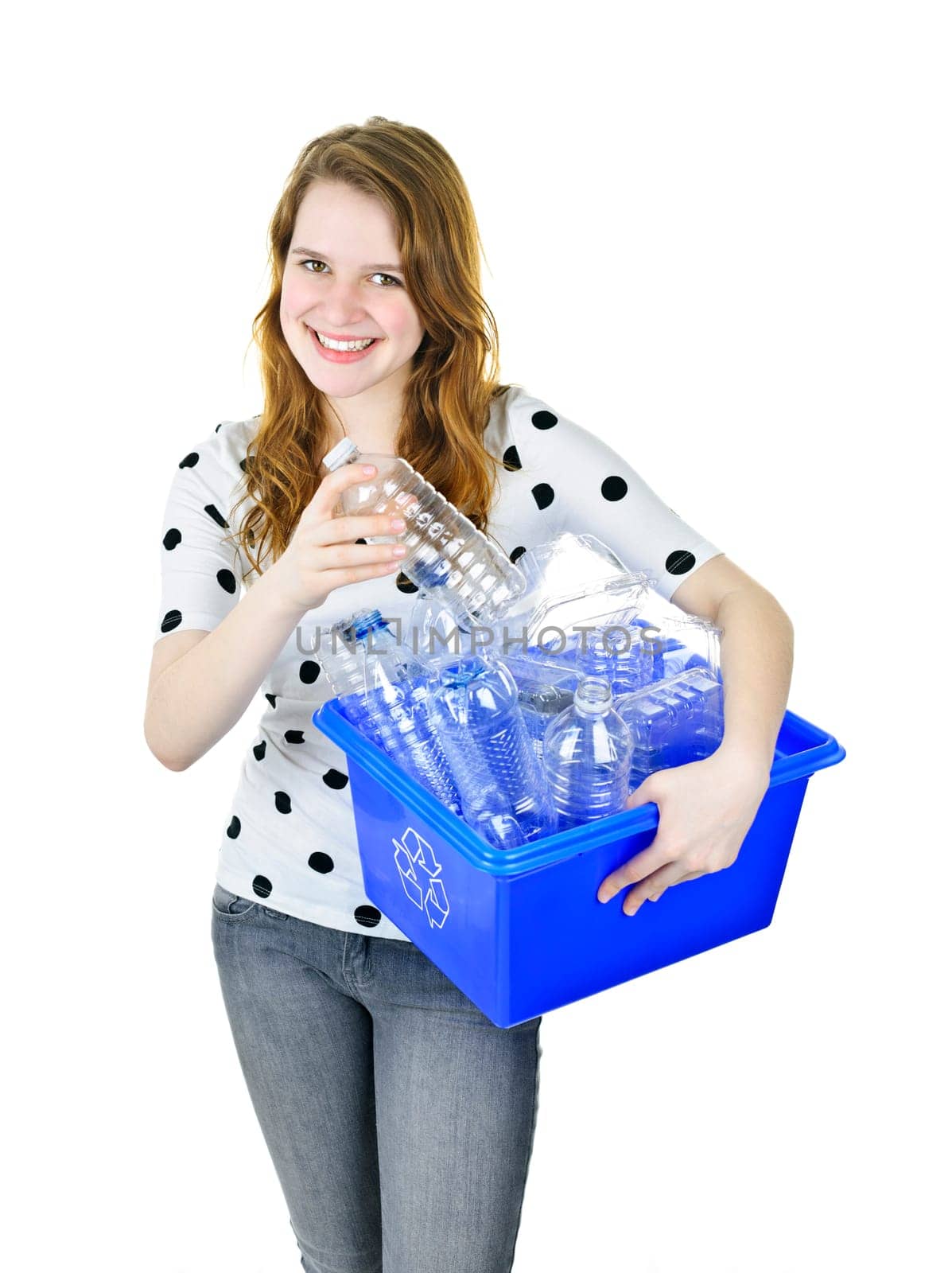 Smiling young woman putting plastic bottle into recycling box