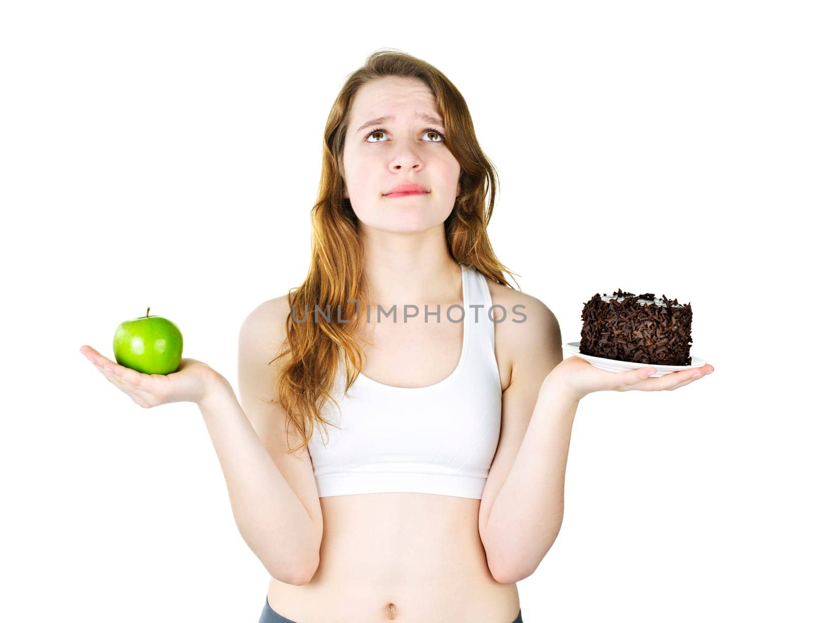 Tempted young woman holding apple and chocolate cake making a choice
