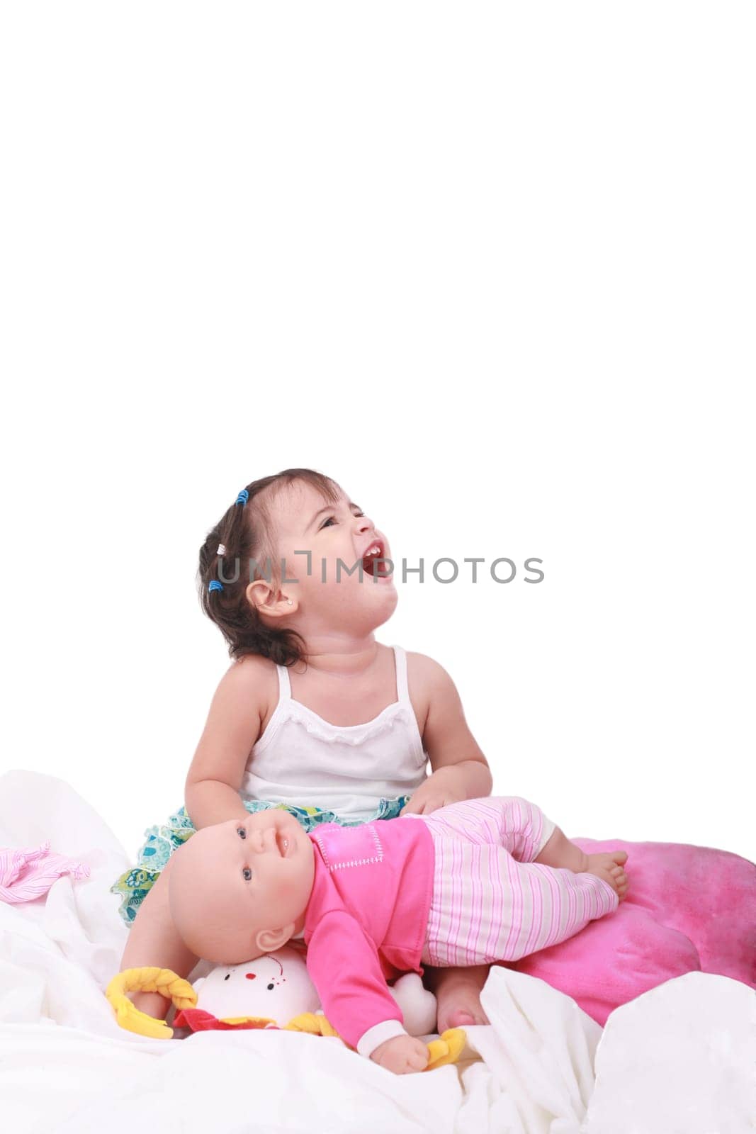 happy little baby girl sitting in the bed with her dolls