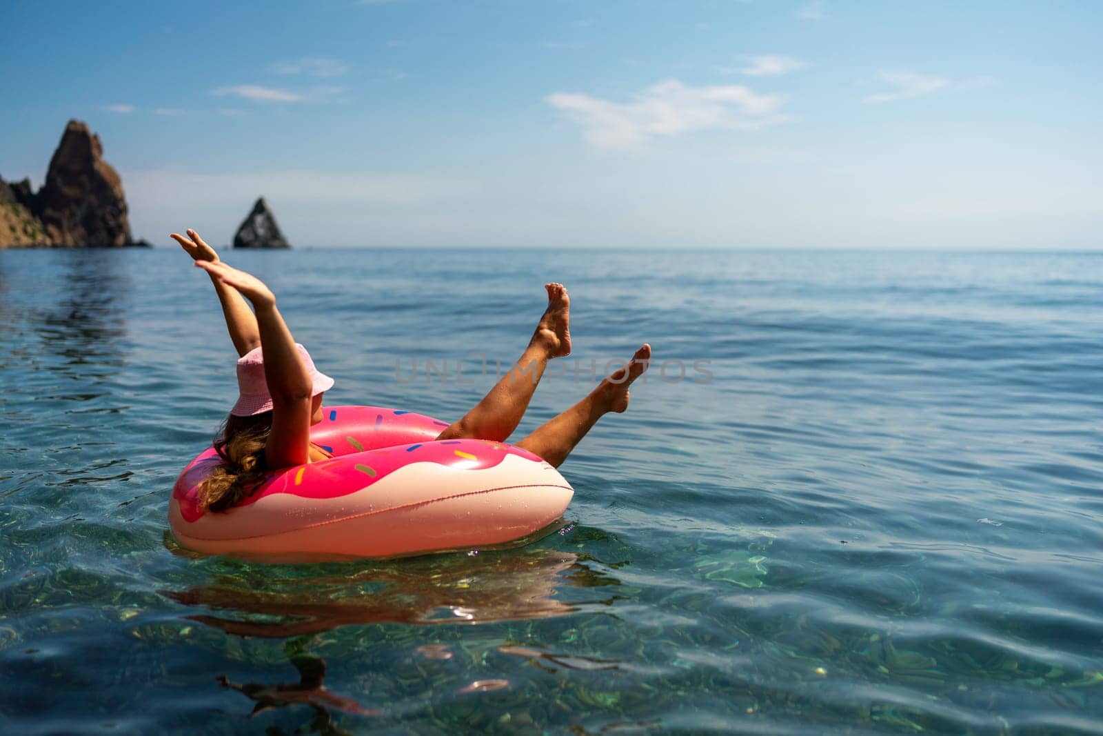 Summer vacation woman in hat floats on an inflatable donut mattress. Happy woman relaxing and enjoying family summer travel holidays travel on the sea