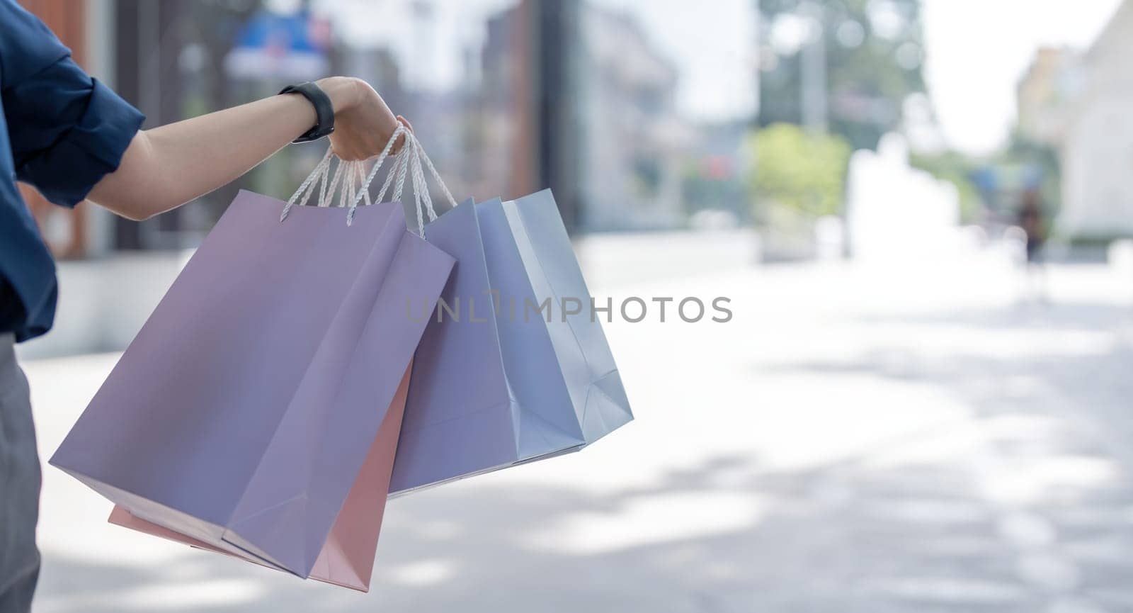 Close up of woman hand holding shopping bags while walking near mall.