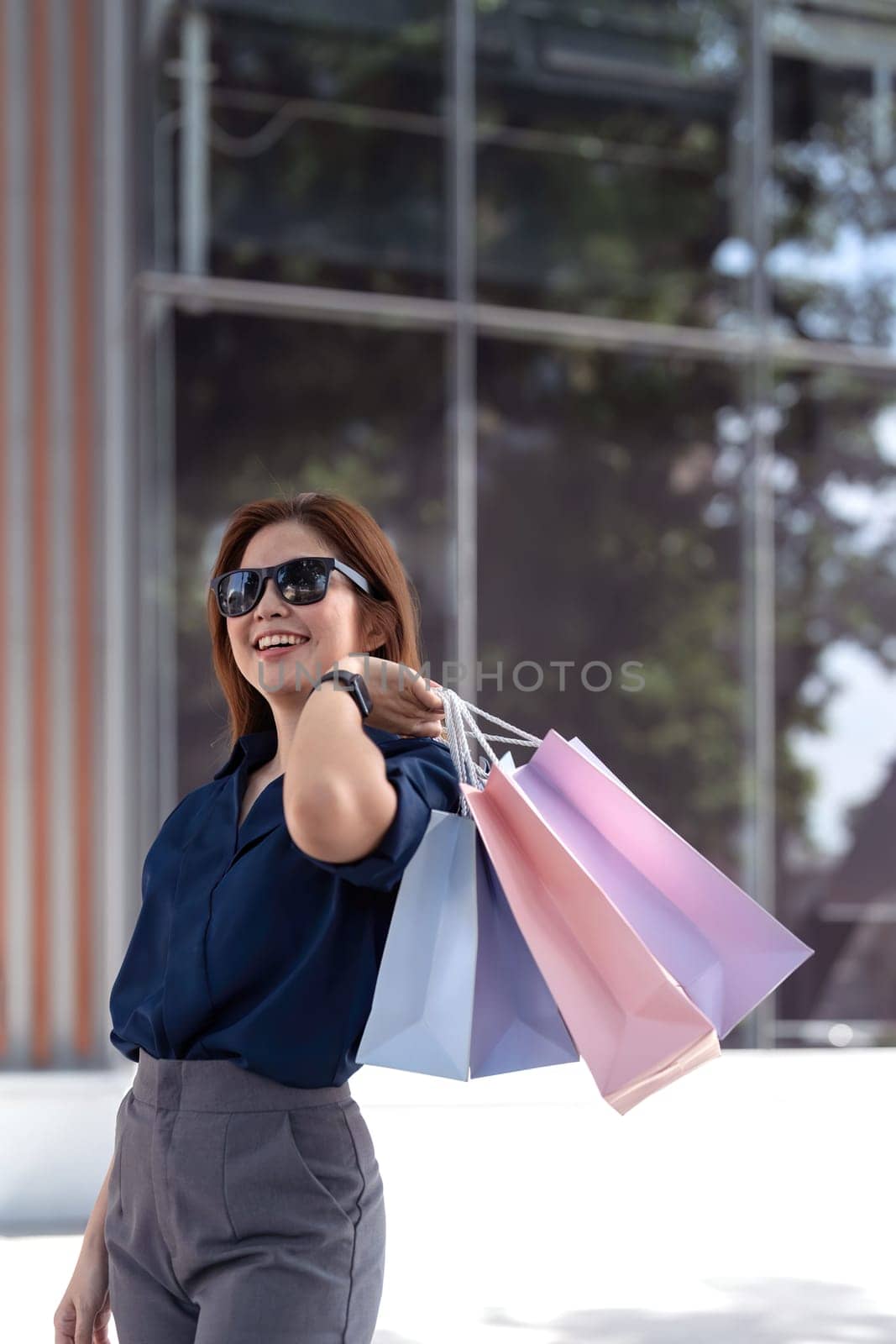 Happy beautiful young stylish woman with shopping bags while walking near mall on holiday.