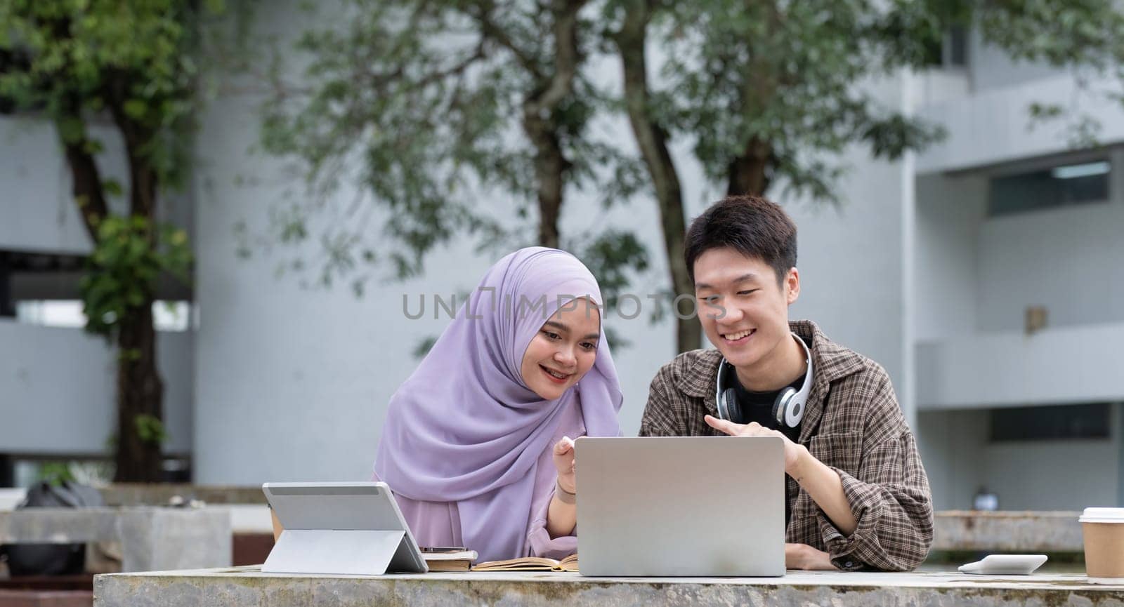 Happy multiethnic group of teenage students talking about the homework after the class at university campus. Two young people smiling, having a friendly conversation together by nateemee