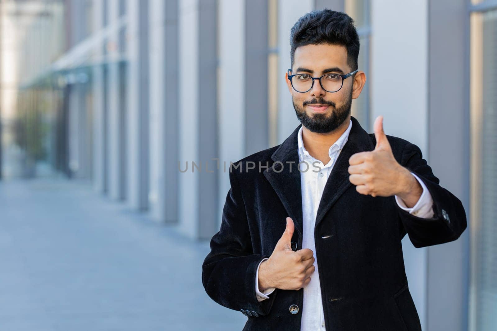 Like. Happy Indian businessman raises thumbs up agrees gives positive reply recommends advertisement likes good idea feedback, celebrating success victory. Arabian Hindu freelancer guy in city street