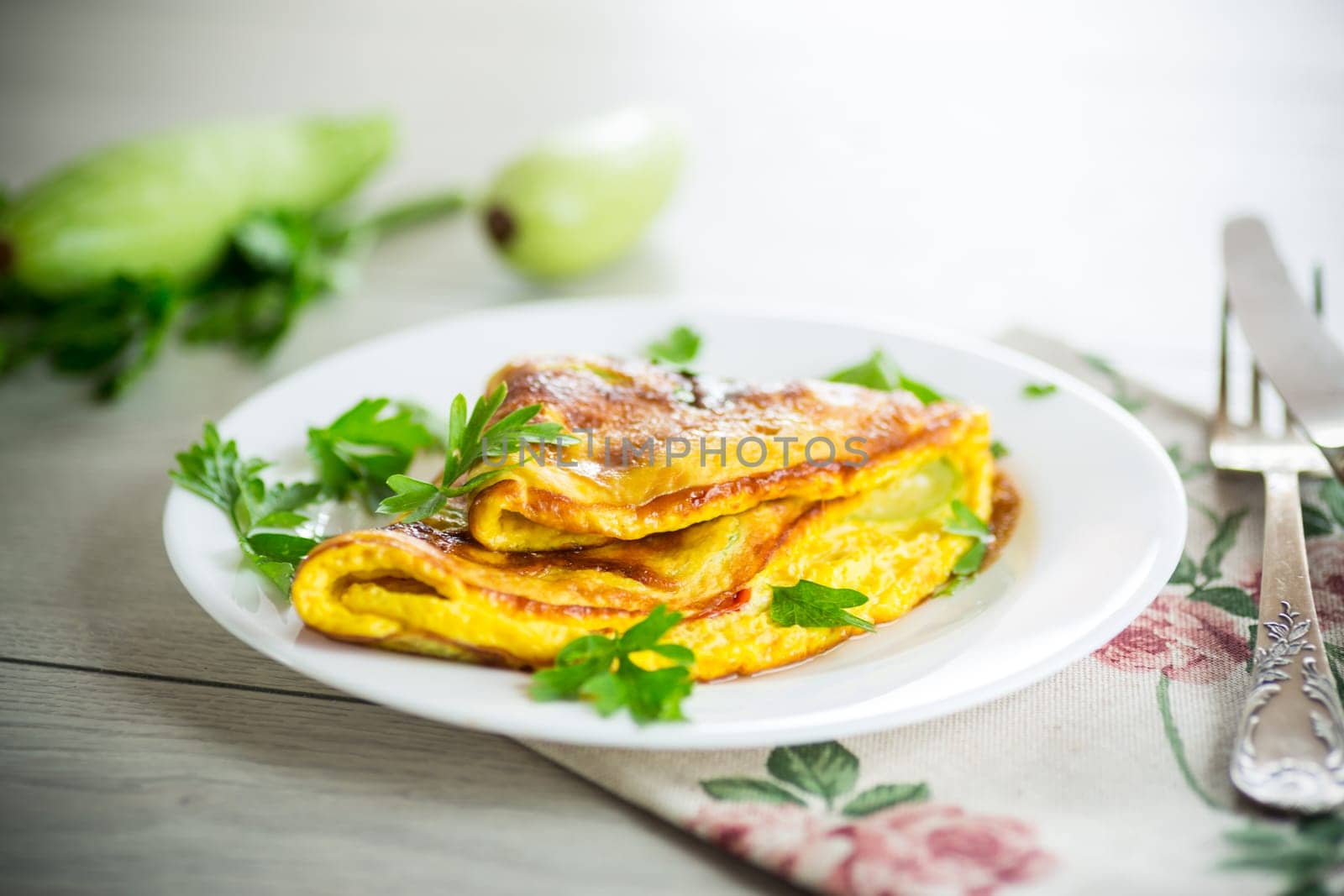 Fried omelet with zucchini,in a plate on a wooden table.