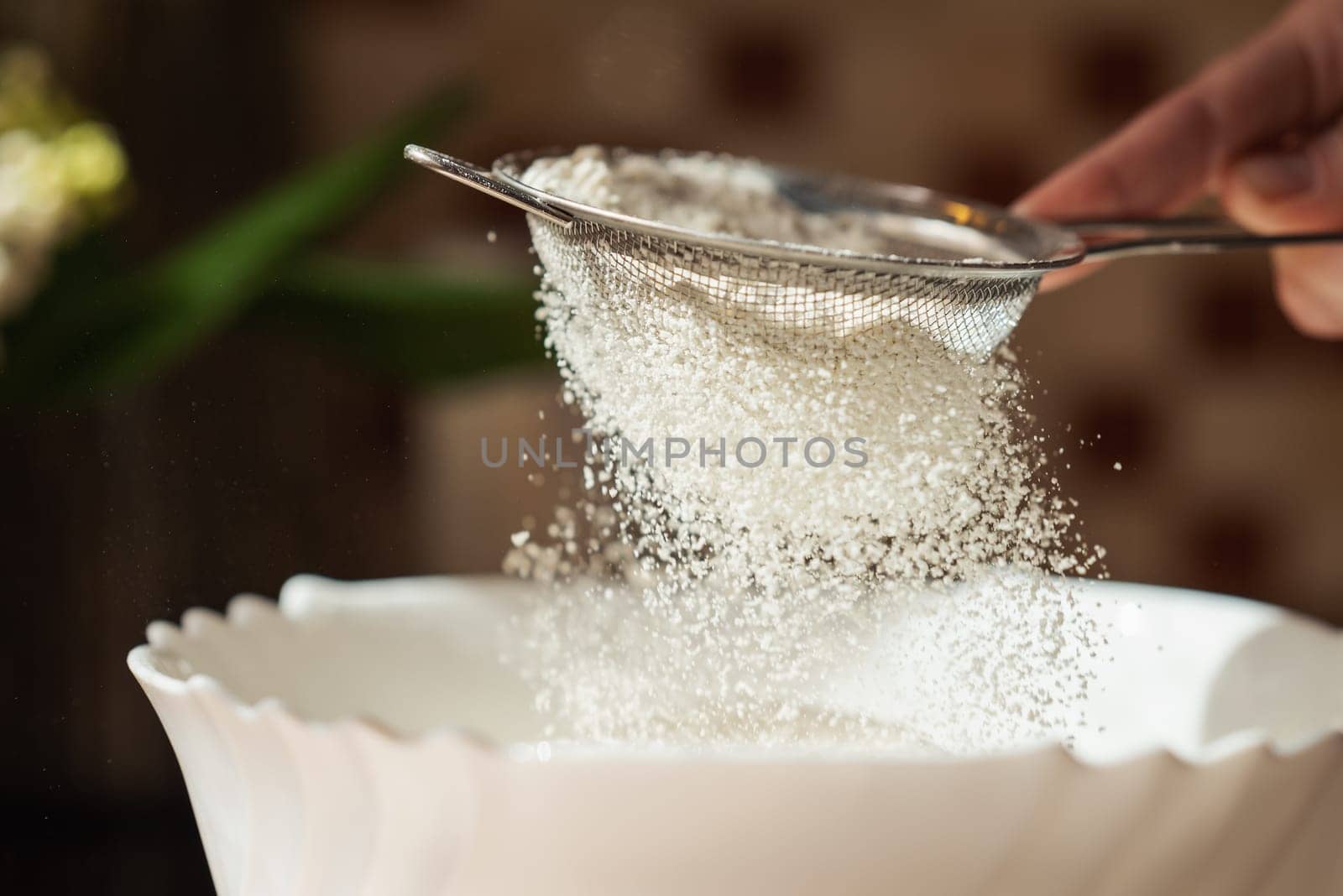 Close up of woman chef hands sifting the flour for making dough, flour cloud in the air