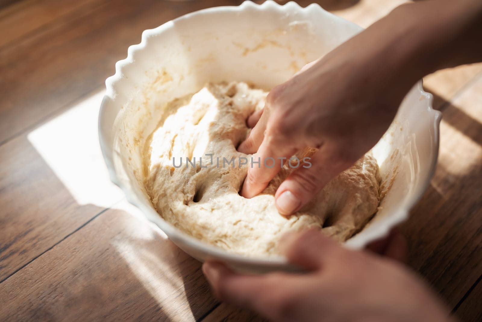 Female hands kneading dough in the bowl, close up by VitaliiPetrushenko