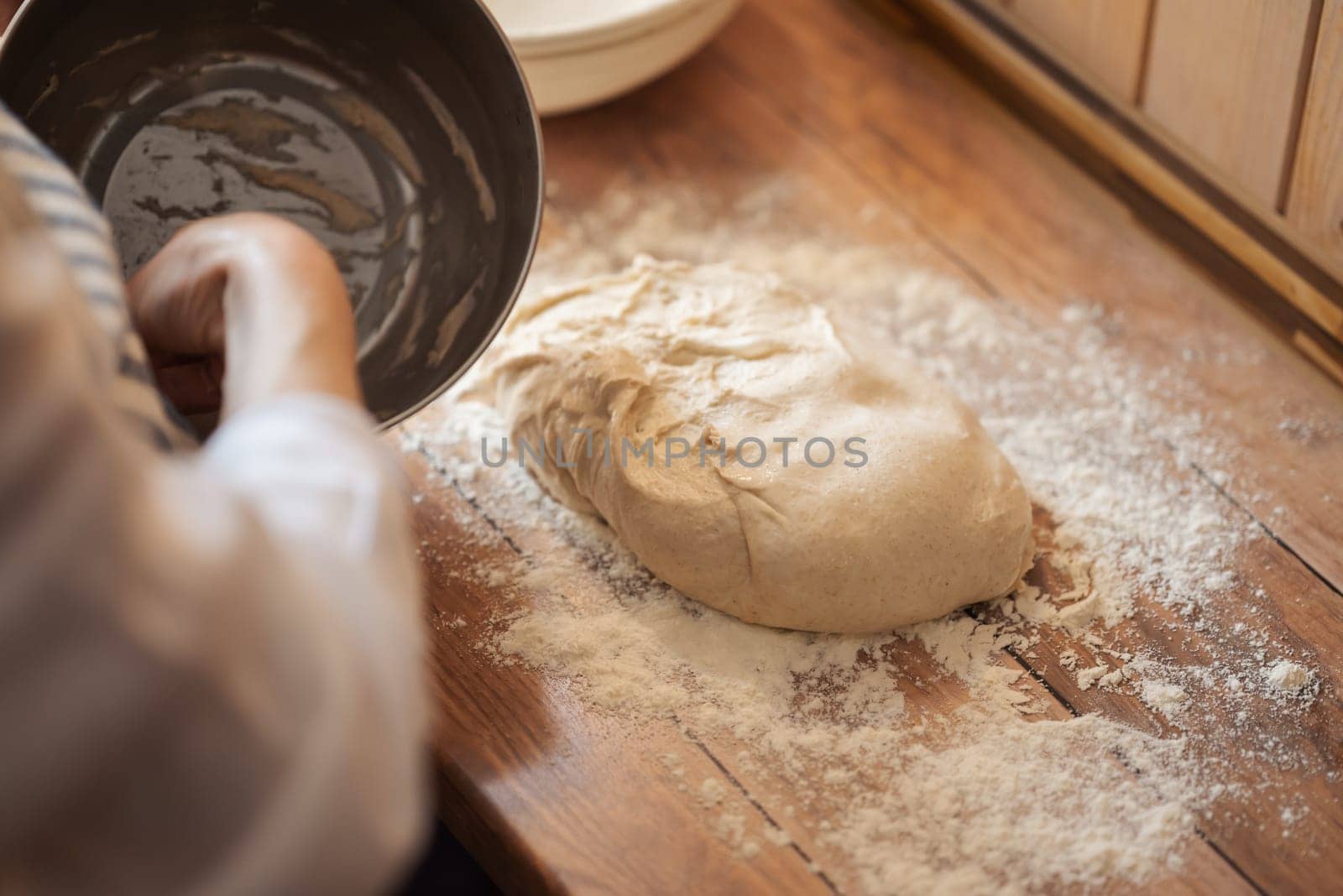 Woman working with raw dough in the kitchen, close up by VitaliiPetrushenko