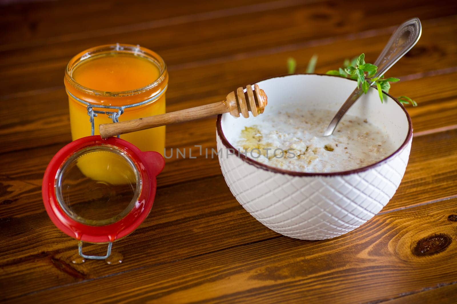 milk oatmeal porridge with honey for breakfast in a bowl on a wooden table.