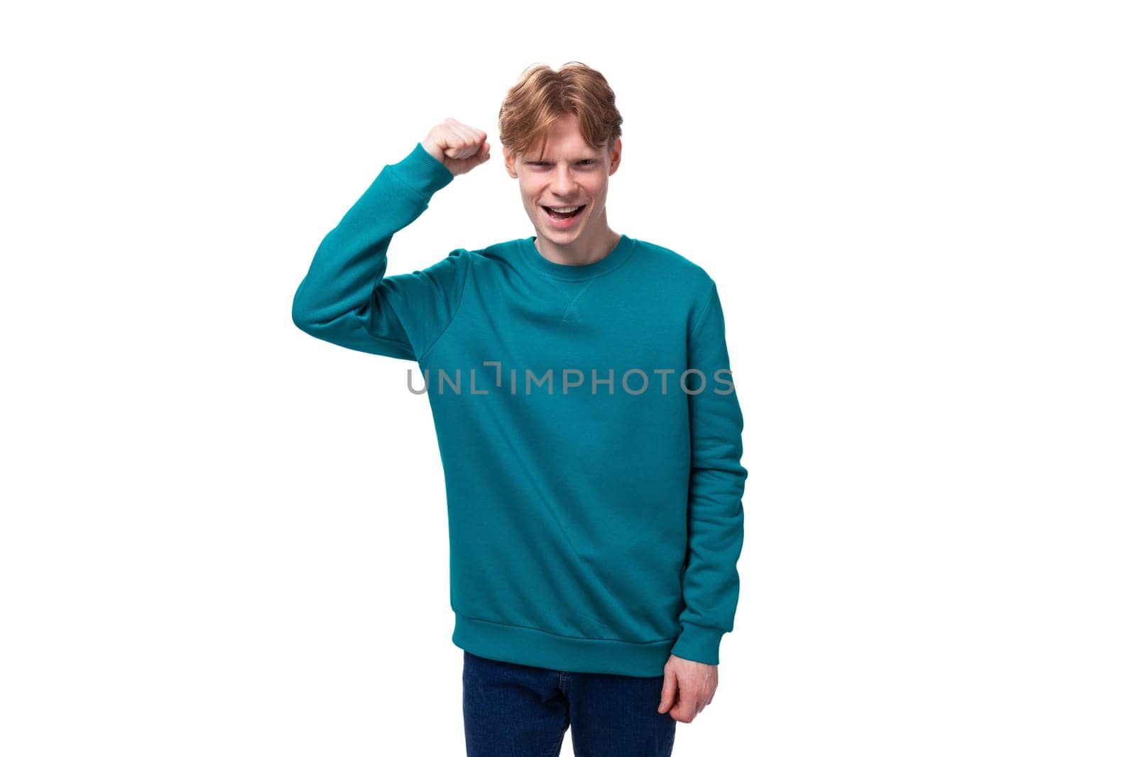 young confident man with red hair dressed in a blue sweater on a white background with copy space.