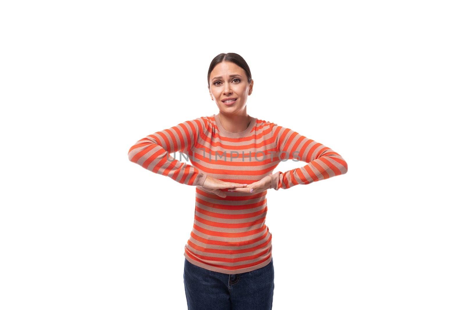 pretty young brunette woman dressed in tight orange sweater on white background with copy space.