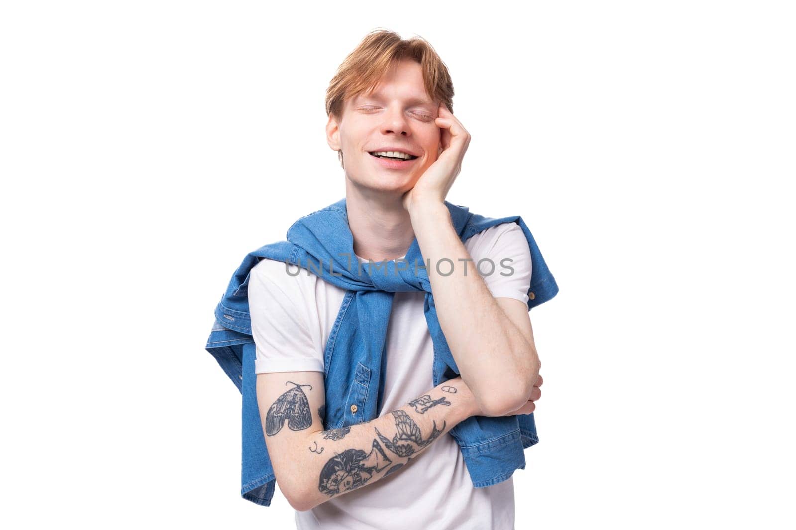 close-up portrait of a young fashionable caucasian guy with short red hair with a tattoo on his arms dressed in a white t-shirt.