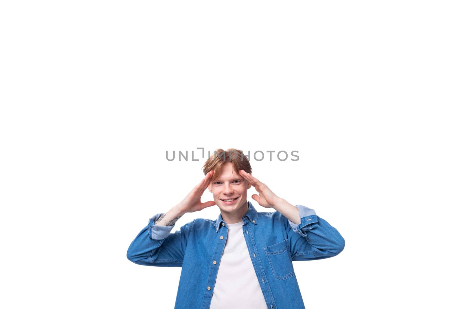portrait of a smiling caucasian red-haired guy in a denim blue denim shirt on a studio background by TRMK