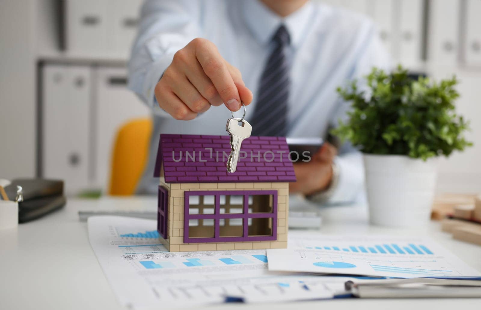 Male hand holds the key to the lock in the hand against the backdrop of the toy house. Sale purchase lease concept real estate services on the market.