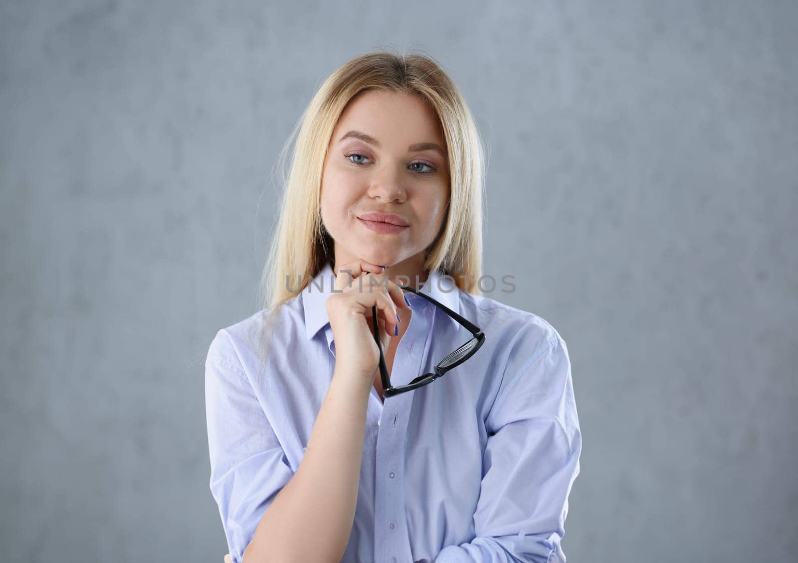 Portrait of a sexy woman in a man's shirt wearing glasses on a gray background looks at the camera. Smiling look advice to give wants objections are not accepted.