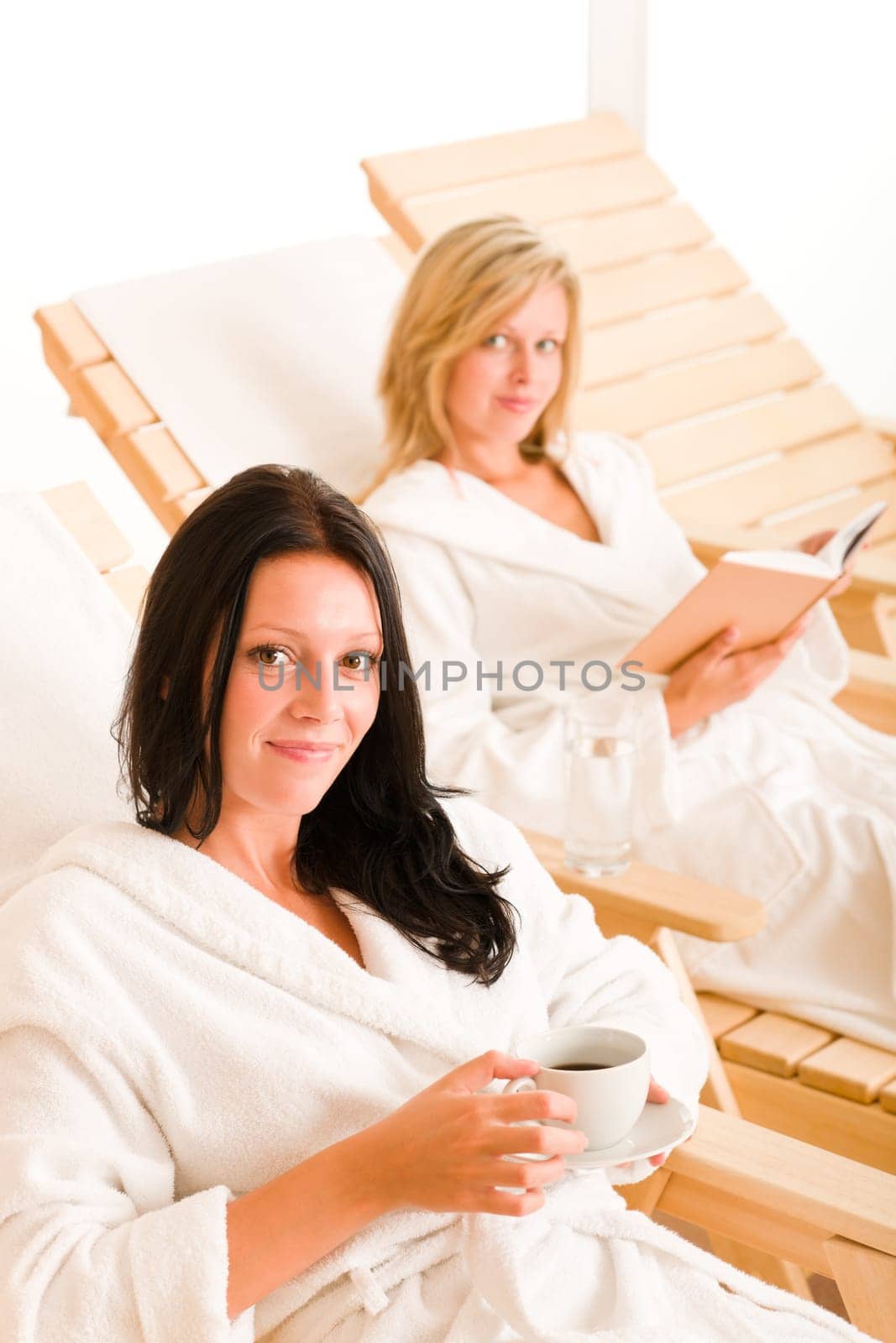 Beauty health spa treatment two women relax sun-beds coffee book