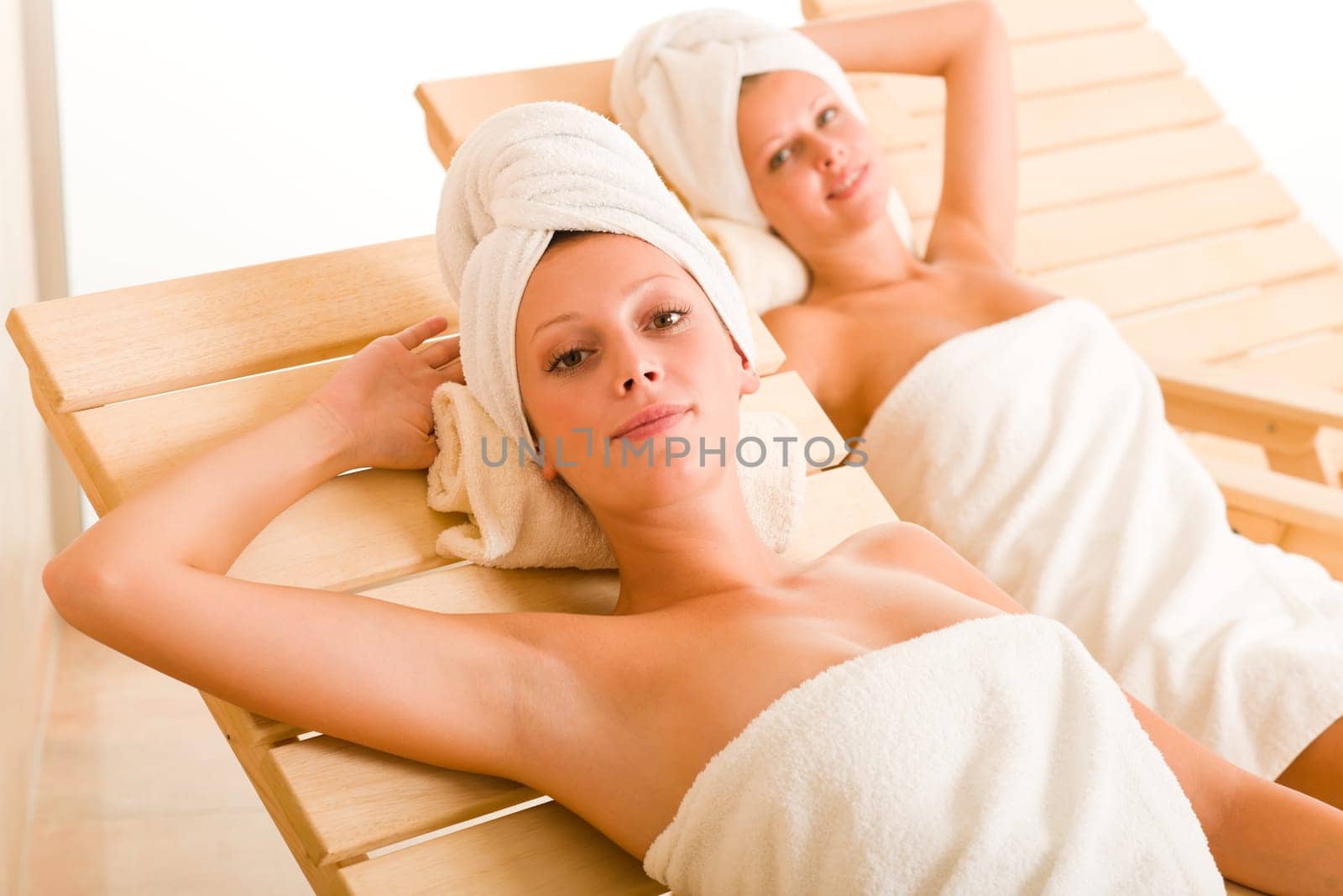 Spa luxury relax room two beautiful women lying on sun-beds