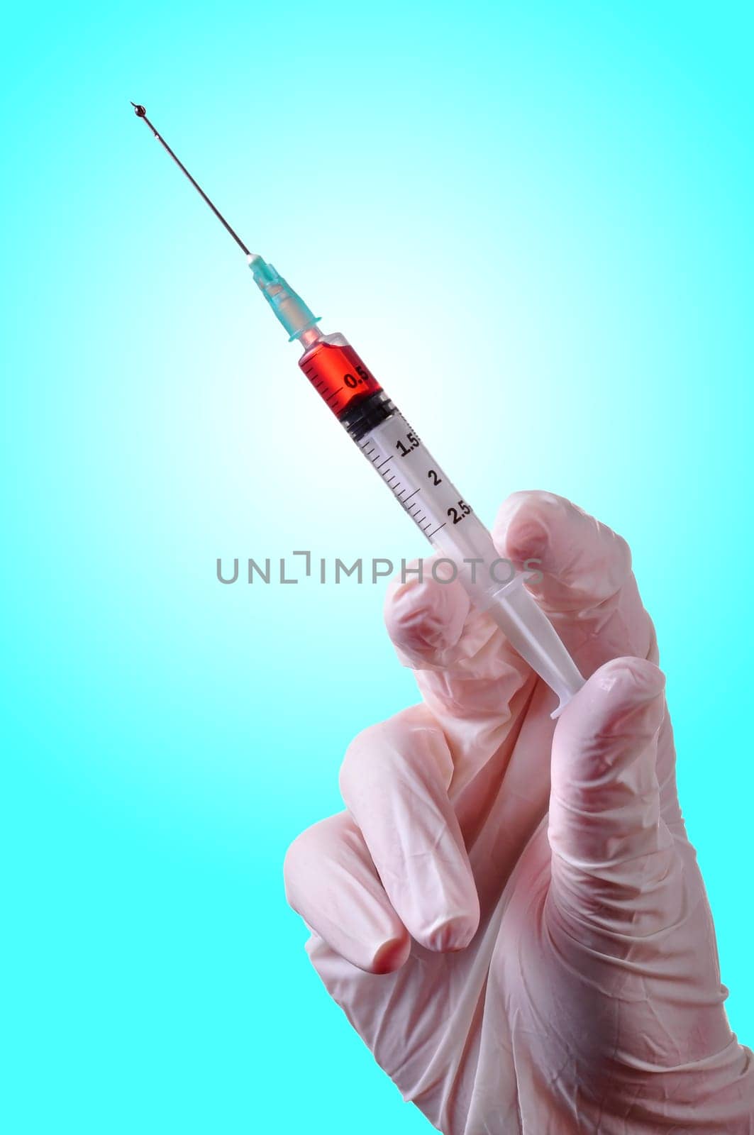 Hand with latex glove holding a syringe with a red liquid inside. Isolated.