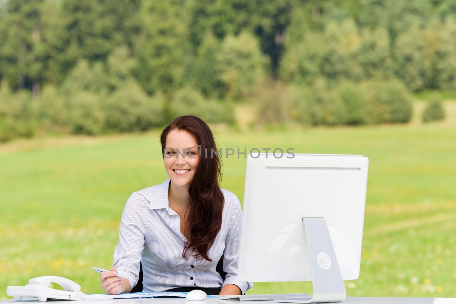 Young businesswoman in nature attractive smiling sitting behind computer table