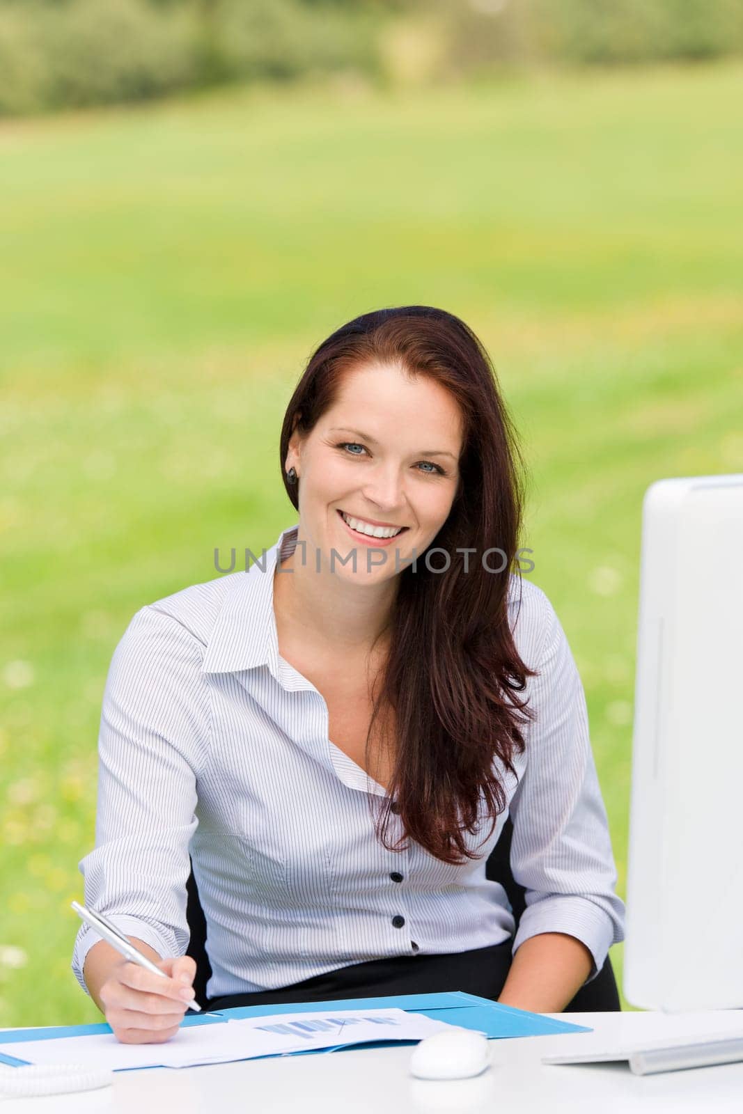 Young businesswoman in nature attractive smiling sitting behind computer table