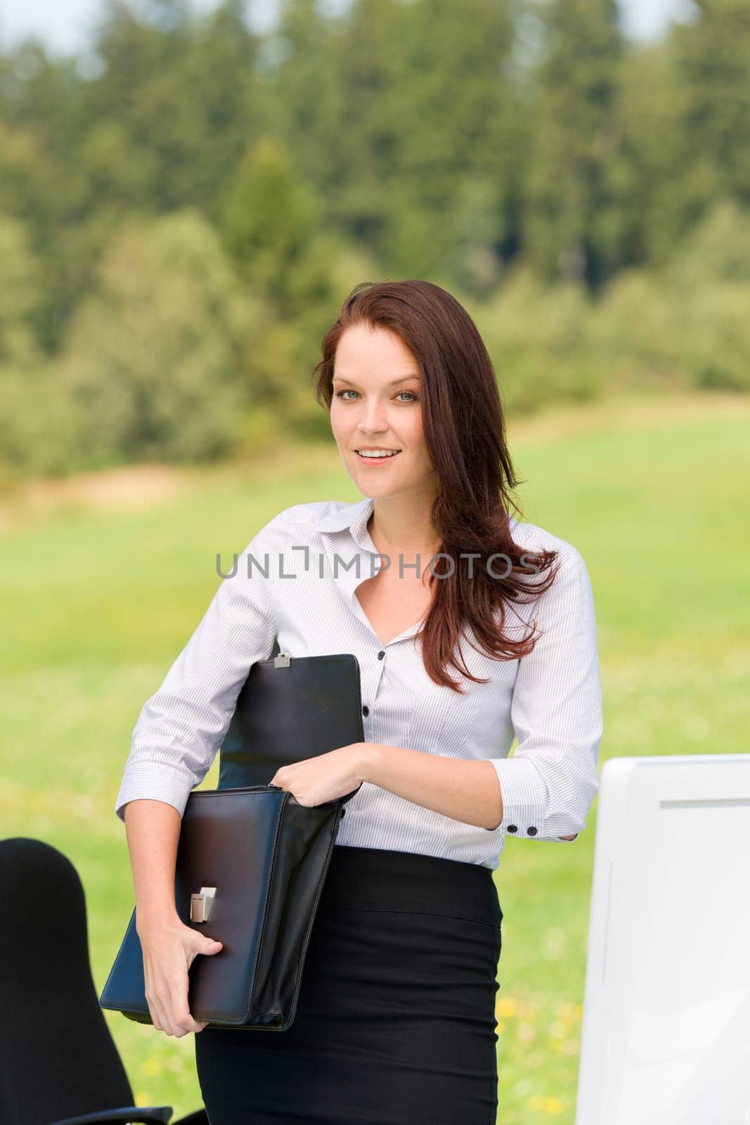 Young businesswoman in sunny nature behind table smiling carry briefcase