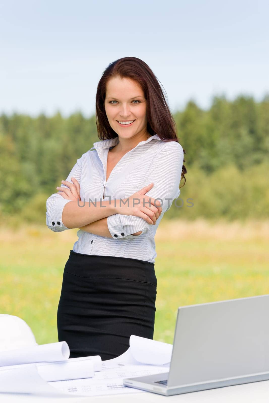 Young architect woman in sunny nature behind table laptop smiling