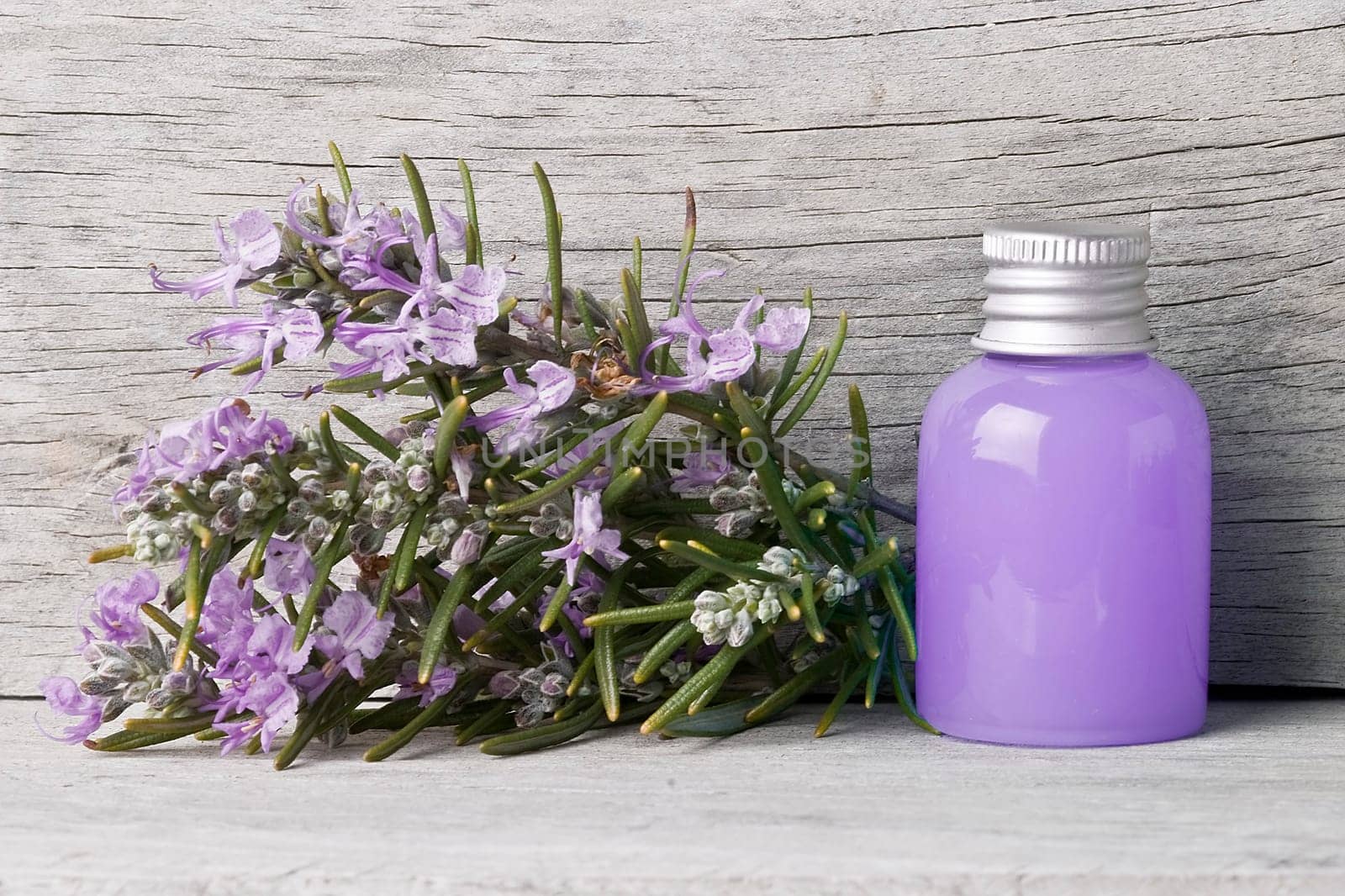 Rosemary branches with flowers and rosemary gel on an old wooden shelf.