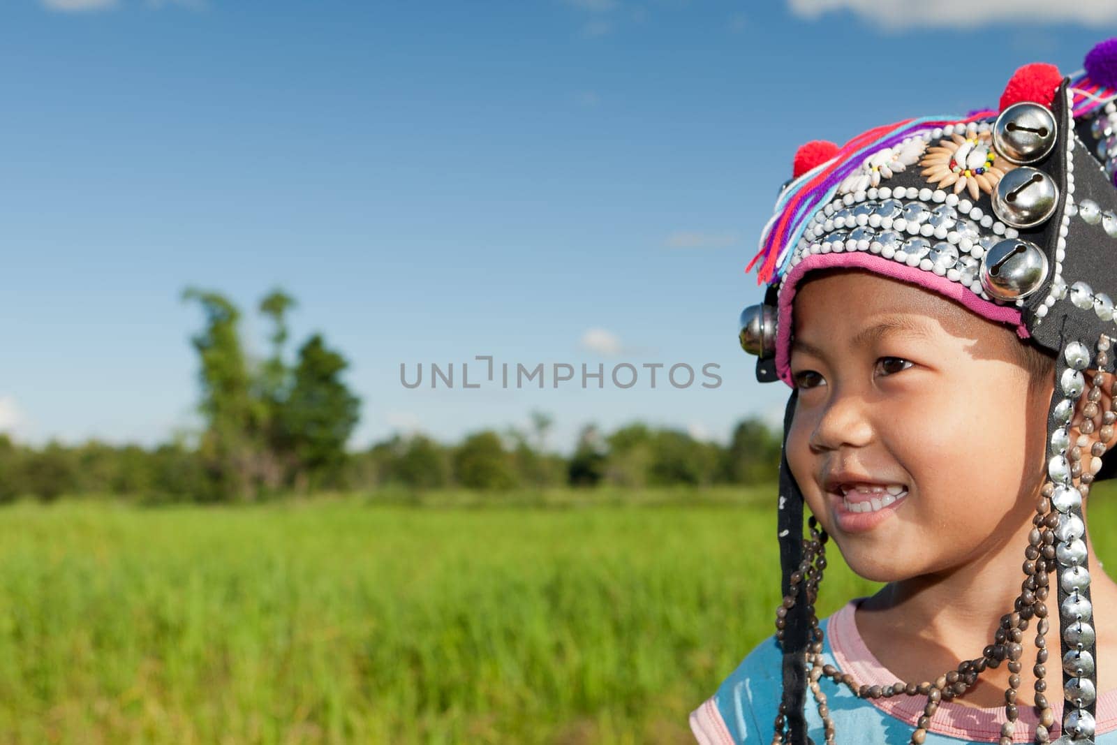 Asian boy Akha,portrait with traditional headgear with rice field in background