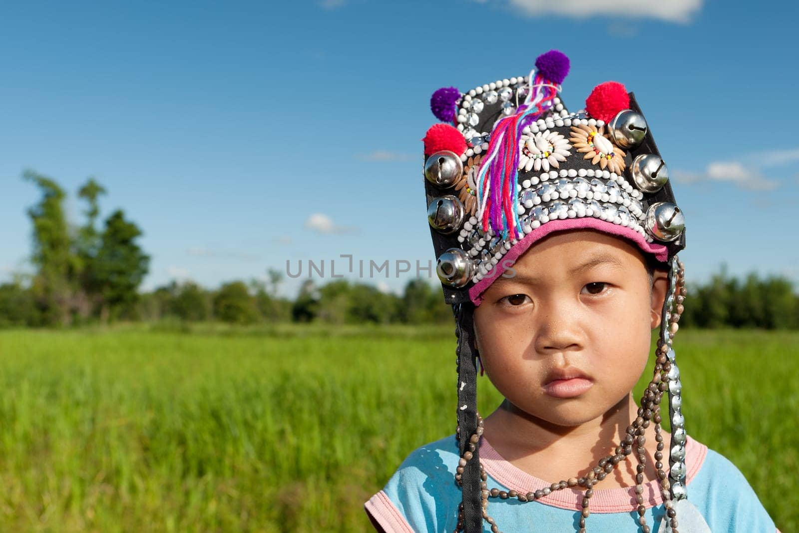 Asian boy Akha,portrait with traditional headgear with rice field in background
