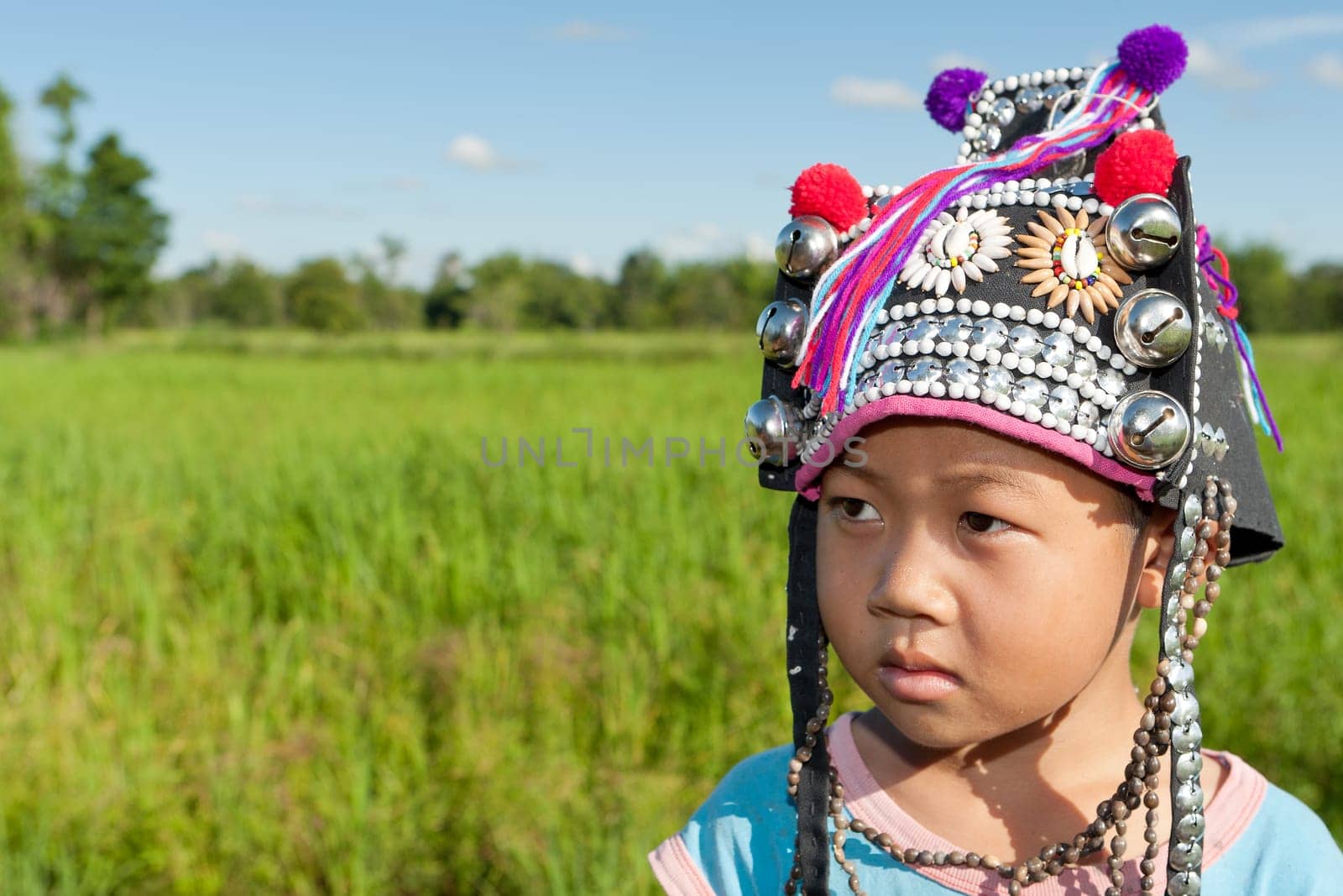 Asian boy Akha,portrait with traditional headgear with rice field in background