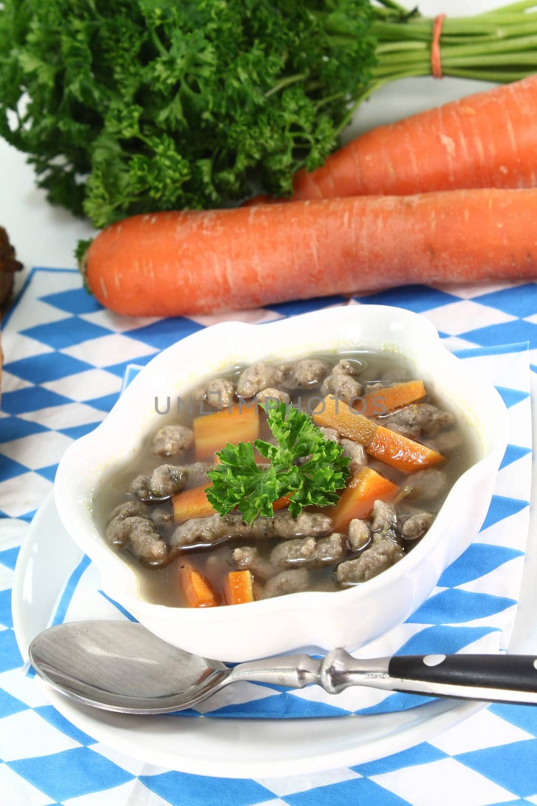a bowl of liver spaetzle soup with carrots and parsley