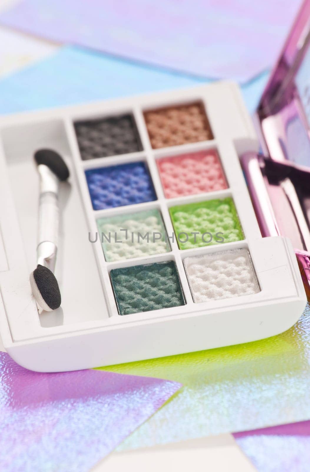 Eye shadow kit over colourful papaers background