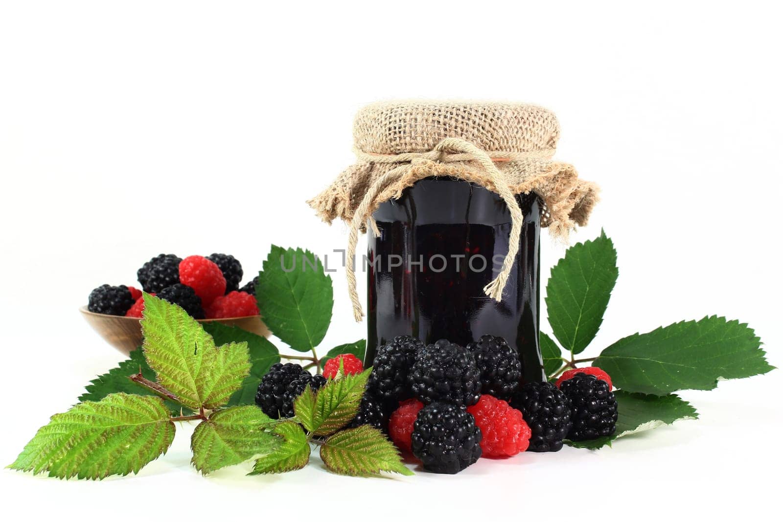 a jar of berry jam and fresh fruit against a white background