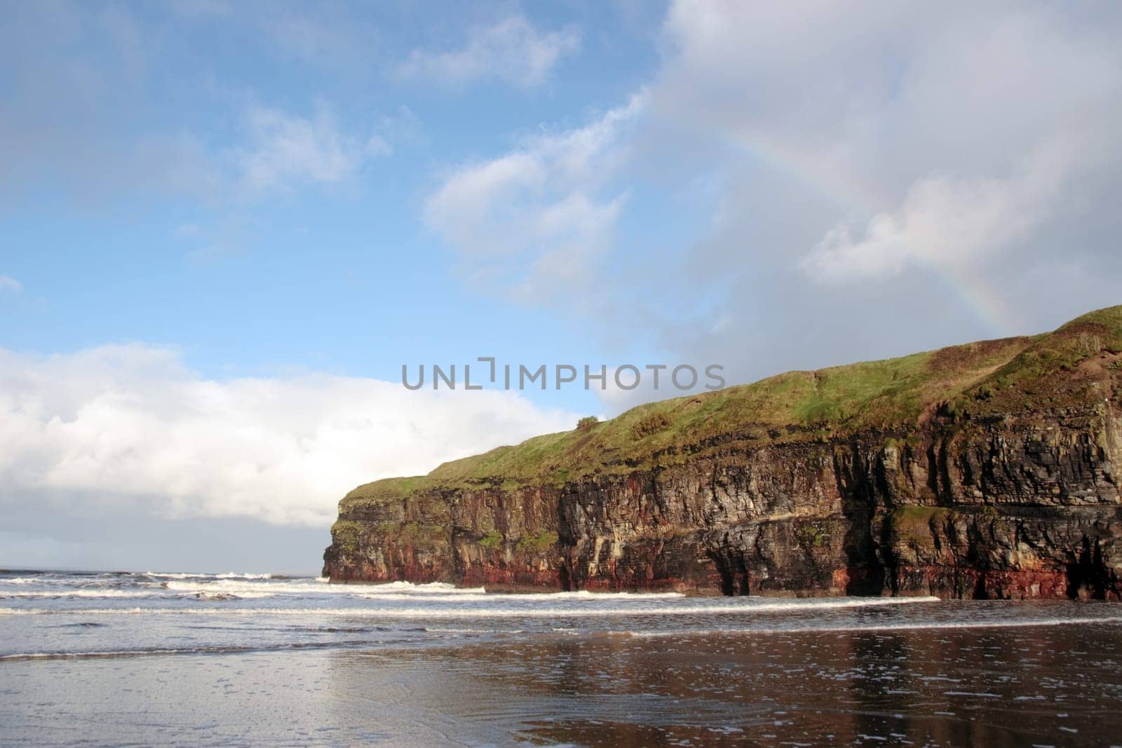 a view of the beach cliffs in ballybunion co kerry ireland with rainbow