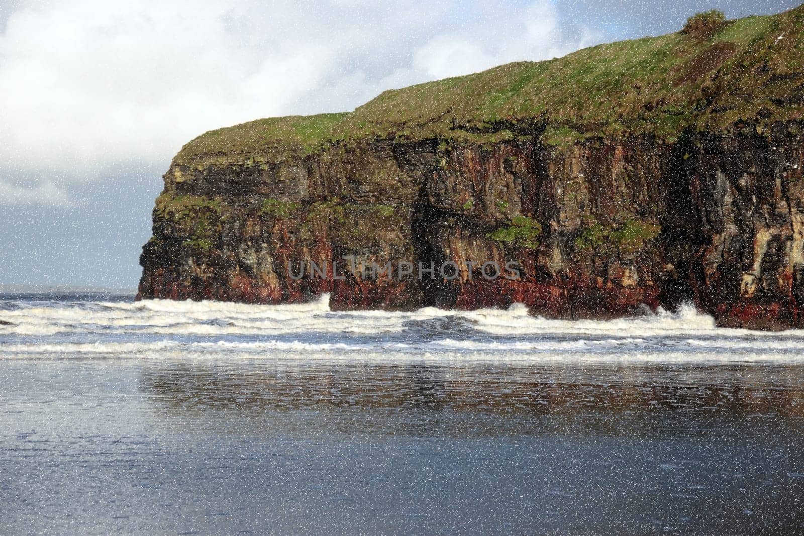 a view of the beach cliffs in ballybunion co kerry ireland with reflection during a snow storm